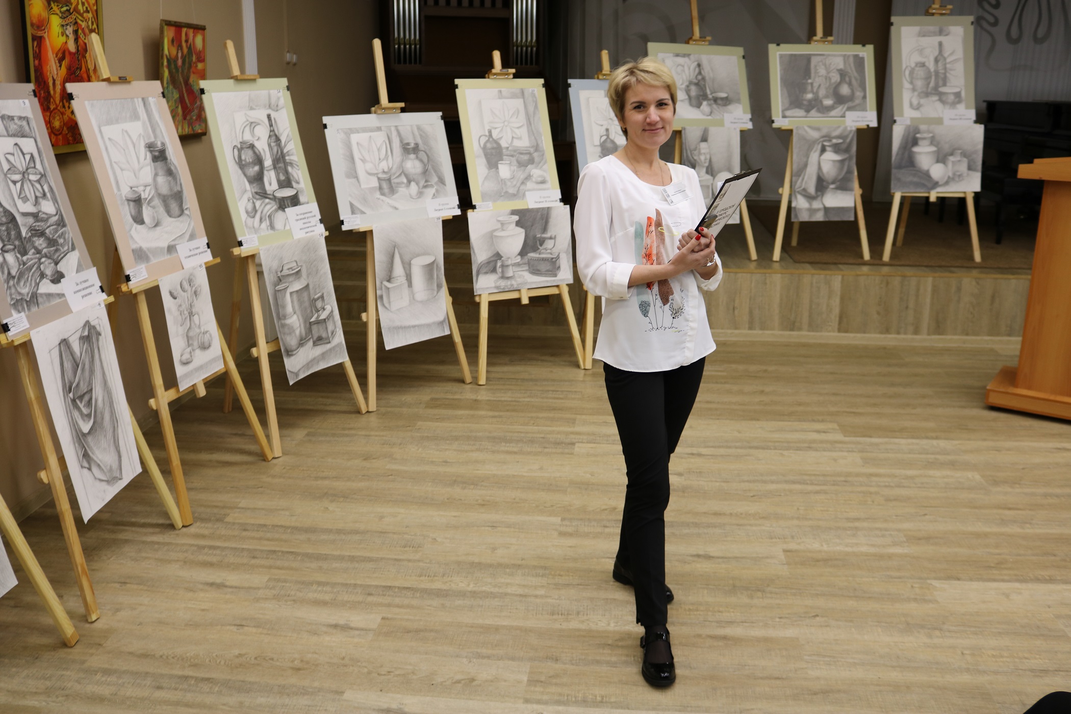 На фото: преподаватель ДШИ №1 Евдокимова Н.В. на фоне выставки конкурсантов